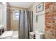 Bathroom showcasing exposed brick, shower-tub combo, and modern fixtures at 3933 Byram Ave, Indianapolis, IN 46208