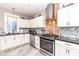 Bright kitchen featuring white cabinets, granite countertops, stainless steel appliances, and brick accent wall at 66 N Ritter Ave, Indianapolis, IN 46219