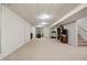 This is a large finished basement area with carpet, white painted walls, an open stairwell, and a small workspace at 1563 Old Thicket Ct, Greenwood, IN 46143