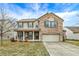 Charming two-story home with a brick and tan exterior, a covered front porch and well-manicured lawn at 1563 Old Thicket Ct, Greenwood, IN 46143