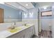 Light blue bathroom featuring a double sink, updated lighting, and tiled shower with neutral colors at 2016 Colt Rd, Indianapolis, IN 46227