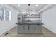 Modern kitchen island with black countertop, light gray cabinets, stainless steel fridge and floating shelves at 218 W 31St St, Indianapolis, IN 46208