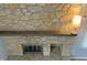 Close-up of a stone fireplace with a dark wood mantle and black firebox at 5746 Overcrest Dr, Indianapolis, IN 46237
