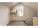 Cozy attic space with neutral carpet and natural light from a window, featuring a wall-mounted AC unit at 1133 Olive St, Indianapolis, IN 46203