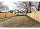 Spacious fenced backyard featuring a mix of grass and fallen leaves, with a glimpse of surrounding houses at 1133 Olive St, Indianapolis, IN 46203