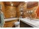 A rustic bathroom offers wood-paneled walls, a built-in tub, a toilet, and a modern vanity with a sink at 4131 N County Road 500 E, Danville, IN 46122