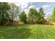 Spacious backyard features a lush lawn, wooden fence, mature trees, and a playset at 5208 Clear Lake Ct, Carmel, IN 46033