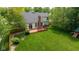 Aerial view of backyard with a wooden deck, mature trees, lush lawn, and privacy fence at 5208 Clear Lake Ct, Carmel, IN 46033