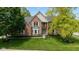 Beautiful two-story brick home with a well-manicured front yard, lush landscaping, and a striking blue front door at 5208 Clear Lake Ct, Carmel, IN 46033