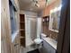 Bathroom with wood paneled walls featuring a shower-tub combo, vanity, open shelving, and a window at 6632 Sargent Rd, Indianapolis, IN 46256
