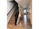 Hallway featuring a staircase with dark banister, wood floor, and bright white walls at 9101 S Stone Trace S Blvd, Avon, IN 46123