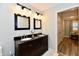 Brightly lit bathroom with double sinks, granite counters, two mirrors, and tan laminate floors at 11710 E 75Th St, Indianapolis, IN 46236