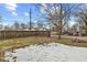 Backyard with some patchy grass, partly covered in snow, enclosed by a chain link and wooden fence at 3950 W Michigan St, Indianapolis, IN 46222
