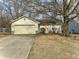 Cozy single-story home featuring a yellow front door, attached garage, and mature trees at 5430 Milhouse Rd, Indianapolis, IN 46221