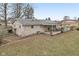 Exterior view of a cozy backyard featuring a covered patio, stone facade and lush lawn at 7482 W Us 40 Hwy, Cumberland, IN 46229