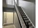Bright stairway with gray walls and carpeted steps featuring black railing and white door to the left at 8048 Garden Ridge Rd, Indianapolis, IN 46237