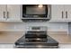 Close-up of stainless steel stove, microwave and range hood against a white tile backsplash at 8218 Elsen Ridge, Avon, IN 46123