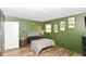 Well-lit bedroom with soothing green walls and a comfortable bed, complemented by wood laminate flooring at 2534 Morning Star Dr, Indianapolis, IN 46229