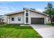 Modern home featuring a sleek design, dark garage door, striking windows, and a well-manicured lawn at 2689 Pearl St, Columbus, IN 47201