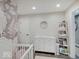 Bedroom area with a crib, changing table with drawers, and floral wallpaper accent at 3659 Watson Rd, Indianapolis, IN 46205