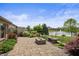Landscaped backyard with a patio area, seat, lake view, and decorative foliage at 4857 W Congress Cv, New Palestine, IN 46163