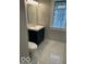 Modern bathroom with dark vanity and toilet, complimented by marble floors and a unique glass block window at 5206 E St Clair St, Indianapolis, IN 46219