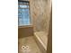 Bathroom featuring white tub and marble tiling around the walls and flooring, lit by a glass block window at 5206 E St Clair St, Indianapolis, IN 46219