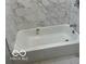 Bright white bathtub and walls with marble tiling, complemented by marble flooring and chrome fixtures at 5206 E St Clair St, Indianapolis, IN 46219