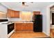 Functional kitchen with wood cabinets, black appliances, and practical laminate flooring at 613 S Mickley Ave, Indianapolis, IN 46241