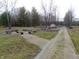 The gravel drive extends to the backyard, near a rustic firepit and a small shed at 6602 S 400 W, Columbus, IN 47201