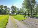View of a gravel driveway lined with mature trees and a firepit in a grassy yard at 6602 S 400 W, Columbus, IN 47201