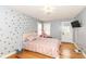 A bedroom with a polka dot accent wall, hardwood floors, and plenty of natural light at 7971 Conarroe Rd, Indianapolis, IN 46278