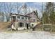View of the multi-level cabin-style home with natural stone accents and gravel driveway at 7971 Conarroe Rd, Indianapolis, IN 46278