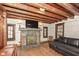 Living room with a stone fireplace, exposed wood beams, hardwood floors, and leather sofa at 7971 Conarroe Rd, Indianapolis, IN 46278