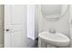 Bathroom with white pedestal sink, chrome faucet, round mirror, and a white door at 848 Kinzer Ave, Carmel, IN 46032