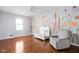 Bedroom with hardwood floors, a window, a crib, and a mural on the wall at 8825 Dunsmuir Dr, Indianapolis, IN 46260