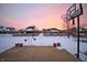 Snow-covered backyard patio with a basketball hoop and views of neighboring houses under a vivid sunset at 1169 Richmond Ln, Greenwood, IN 46143