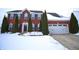 Charming red brick two-story home with a two car garage and evergreen trees in a snowy landscape at 1169 Richmond Ln, Greenwood, IN 46143