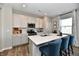 Bright kitchen with modern appliances, white cabinets, and an island with barstool seating. Window with light-filtering curtains at 28 Lively Pl, Cicero, IN 46034