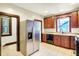 Kitchen with stainless refrigerator, warm wooden cabinets and tiled floors with a view outside at 342 N Arsenal Ave, Indianapolis, IN 46201