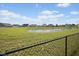 Scenic view of a pond surrounded by green grass and a black chain-link fence at 4236 Stubbington Ln, Indianapolis, IN 46239