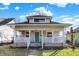 Charming home with a welcoming front porch, white railing, and a vibrant teal door, complemented by a well-kept lawn at 529 W 42Nd St, Indianapolis, IN 46208