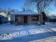Charming single-story home featuring red door and stone accents, front lawn covered in snow at 603 W 33Rd St, Anderson, IN 46013