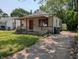 Cozy one-story home featuring a covered porch and mature trees surrounding the property at 603 W 33Rd St, Anderson, IN 46013