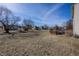 Expansive backyard with a wooden deck, a small playhouse, and mature trees under a clear blue sky at 6116 Bartley Ct, Indianapolis, IN 46236