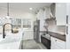 Kitchen featuring white cabinetry, farmhouse sink, stainless steel appliances, and backyard view at 6420 E 116Th St, Fishers, IN 46038