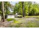 Exterior shot of garages and an additional storage shed on a gravel lot surrounded by trees at 7082 Muskrat Dr, Nineveh, IN 46164