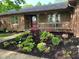 Charming single-story home featuring a brick and wood facade with lush landscaping in the front yard at 8316 Hill Gail Dr, Indianapolis, IN 46217