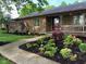 Charming brick home with a landscaped front yard, featuring lush greenery and a welcoming porch at 8316 Hill Gail Dr, Indianapolis, IN 46217