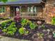Landscaped front yard with mulch, plants, flowers, and a covered porch with a red door at 8316 Hill Gail Dr, Indianapolis, IN 46217